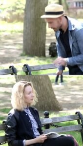 Man starting a conversation with a woman on a park bench in NYC