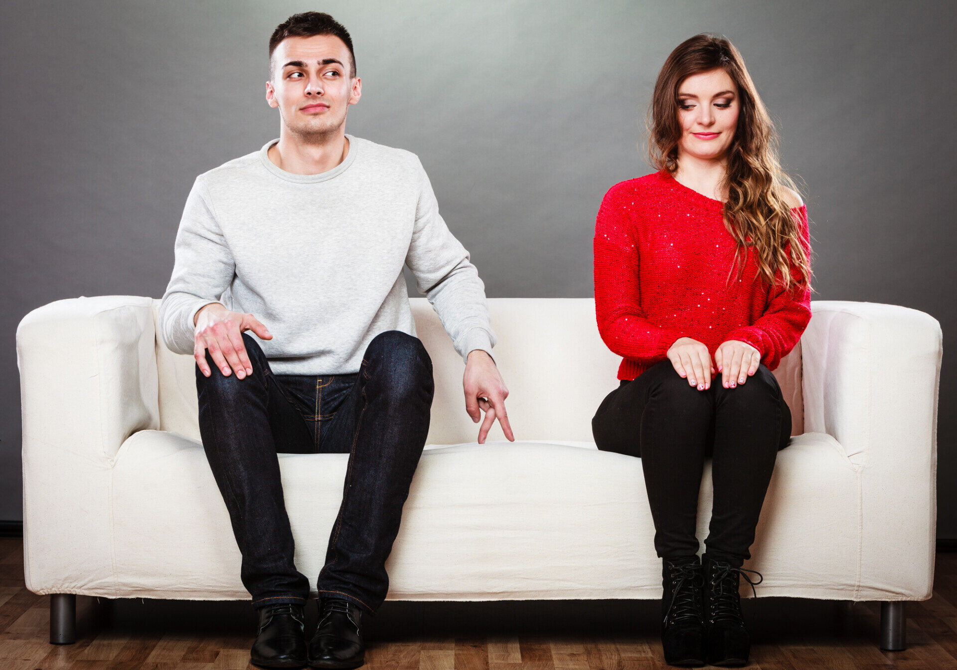 Shy woman and man. Guy sitting near attractive young woman on sofa and making hand gesture walking with finger to girl